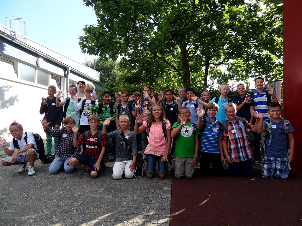 Klassenfoto einer neuen fünften Klasse mit Schulranzen auf dem Schulhof.